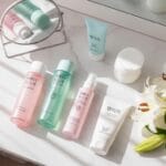 Woman with glowing skin and Korean skincare products in a bright, minimal setup showing steps of a simple skincare routine.