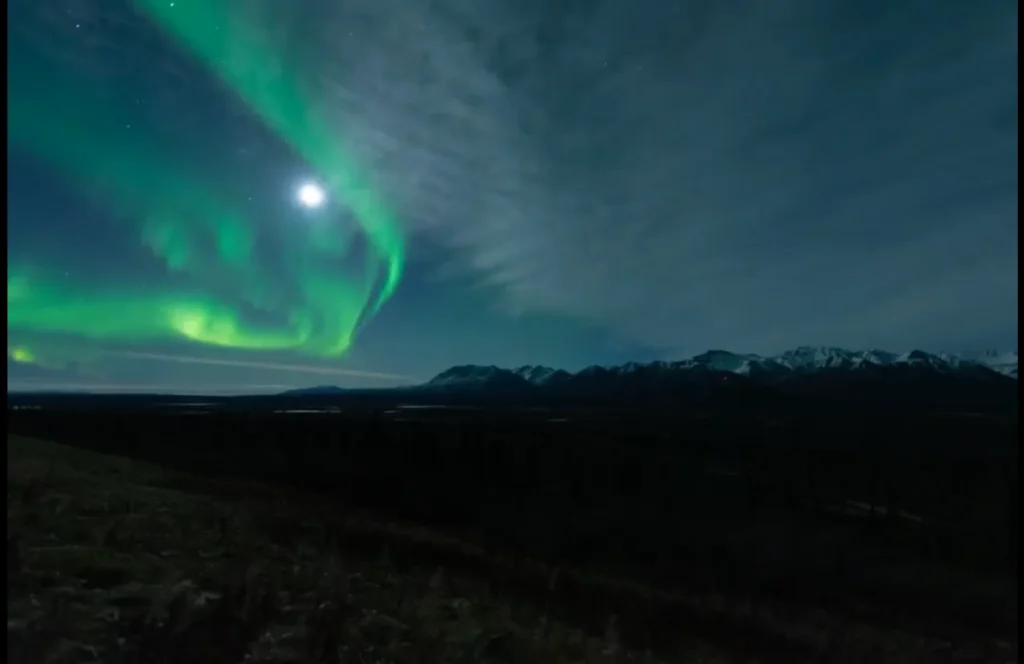 Northern Lights Tonight: Best Locations and Times for Viewing in 2025 2 Vibrant green northern lights dancing over snow-capped mountains under a starry sky